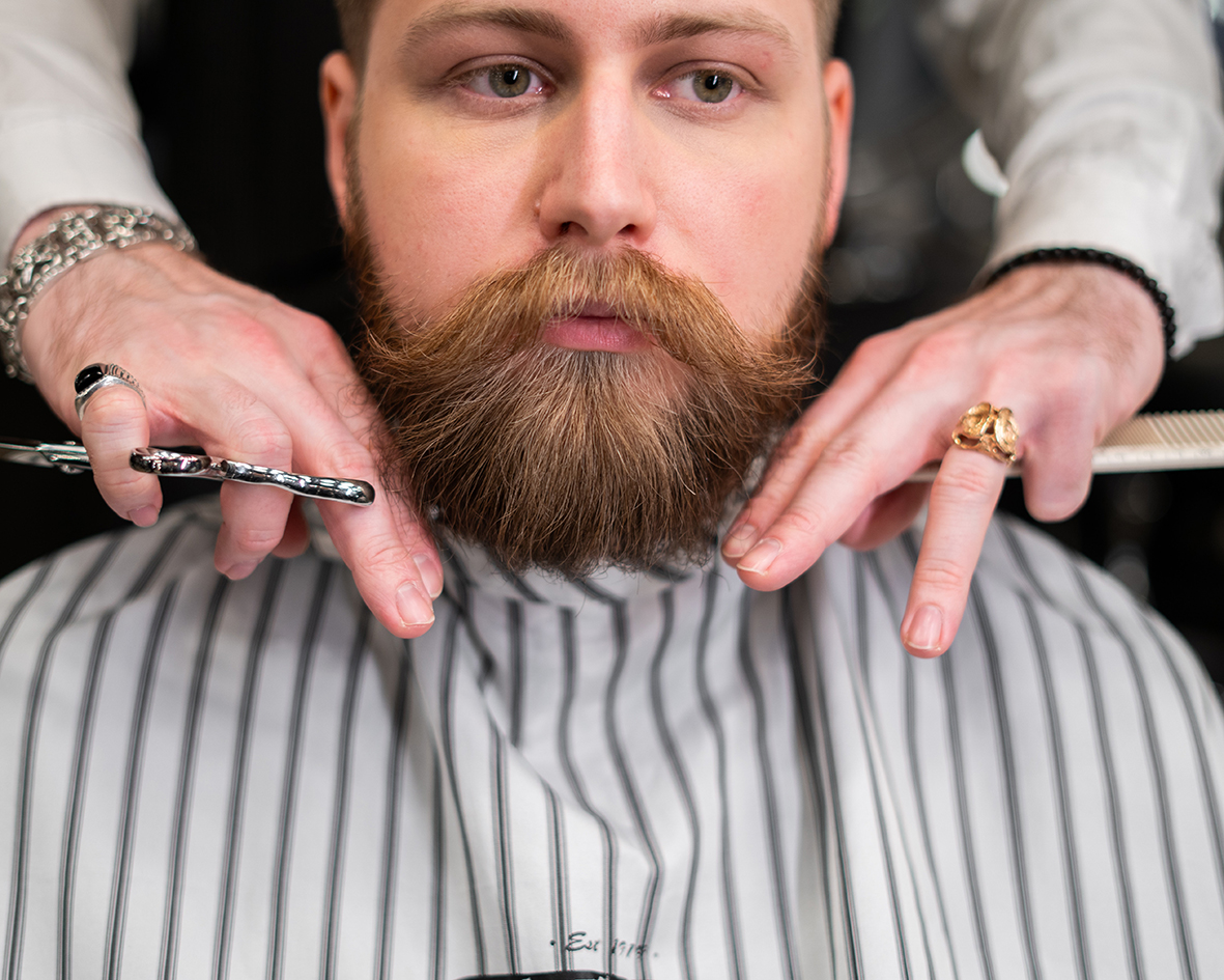 Zákazník u holiča necháva upraviť ho svoju bradu pomocou balzamu na fúzy.